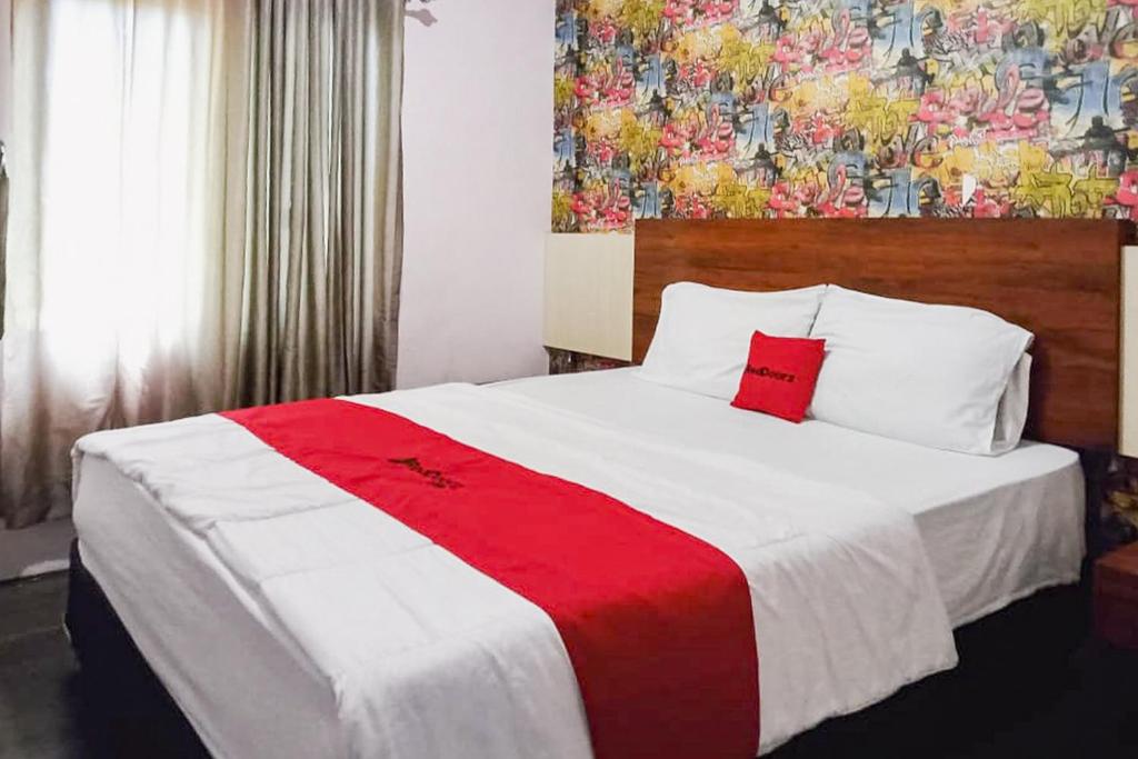 a bedroom with a large bed with a red and white blanket at RedDoorz at Pantai Panjang Bengkulu 2 Citandui in Bengkulu
