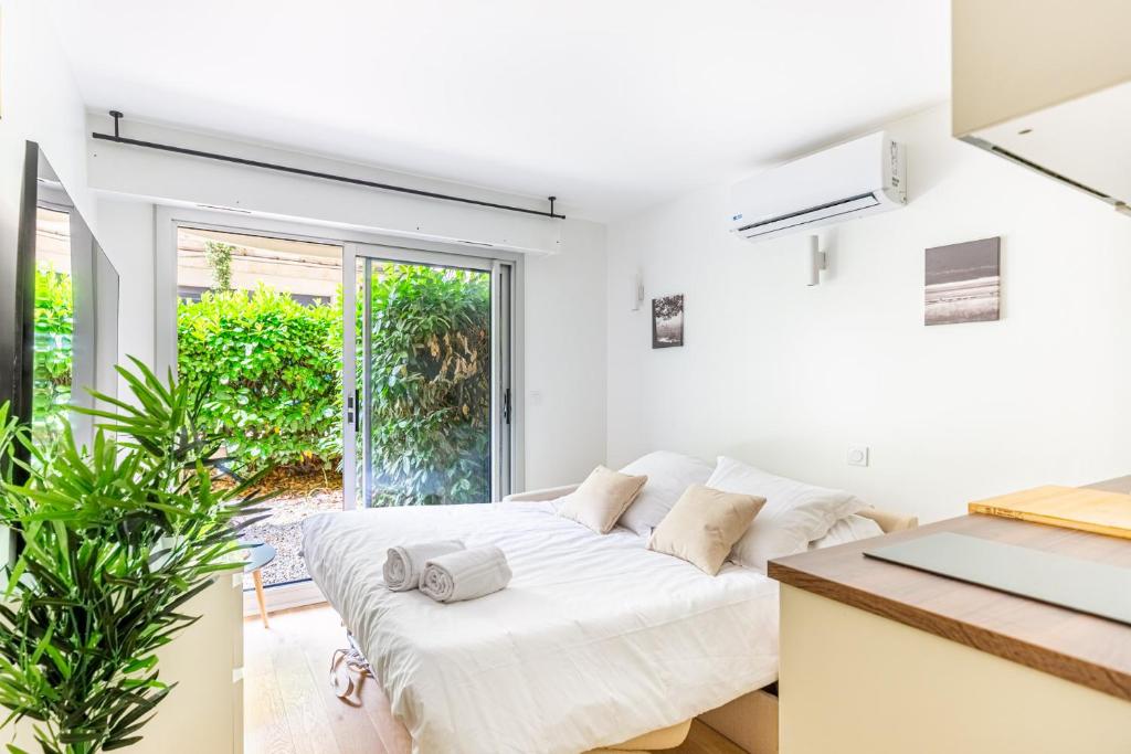 - un salon blanc avec un canapé blanc et une fenêtre dans l'établissement Lavie Maison Studio avec Jardin, à Bordeaux