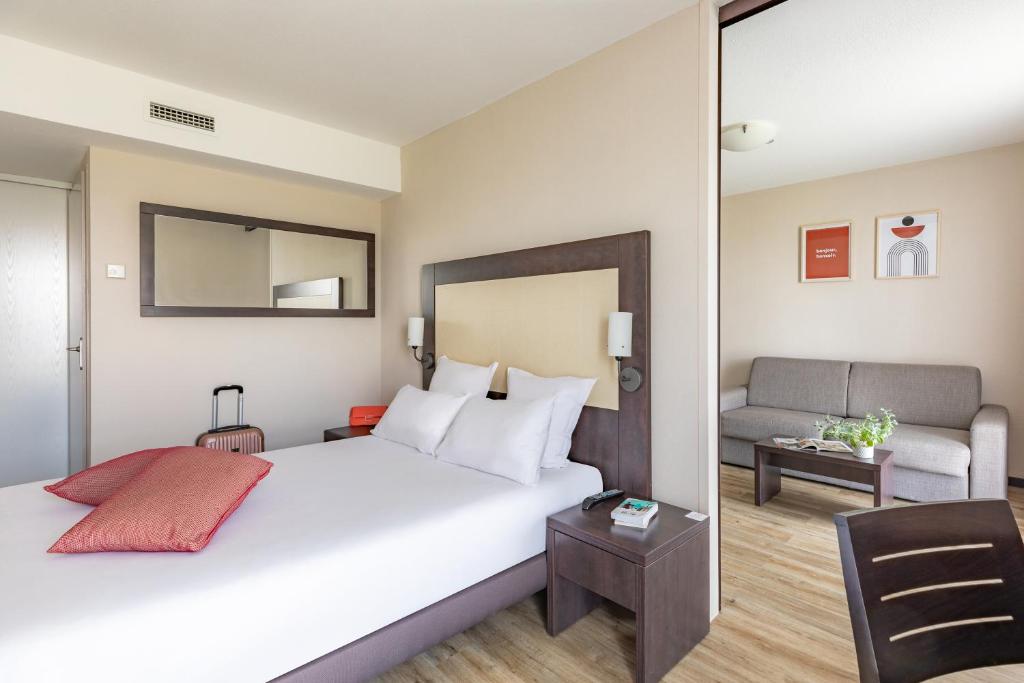 Habitación de hotel con cama y sofá en Appart’City Confort Nantes Ouest Saint-Herblain en Saint-Herblain