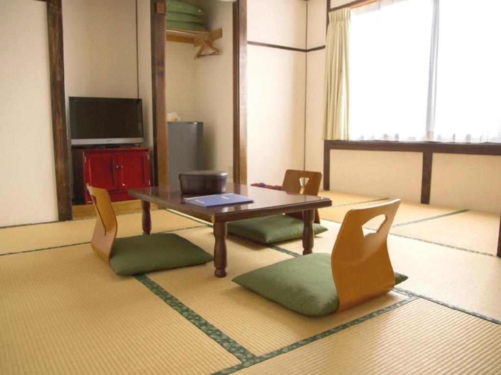 uma sala de estar com uma mesa e cadeiras e uma televisão em Ryokan Seifuso - Vacation STAY 85475v em Matsumoto