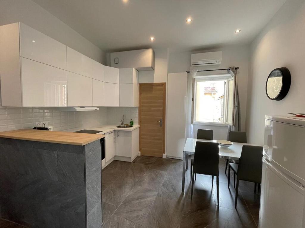 une cuisine avec des armoires blanches et une table et des chaises dans l'établissement Massena : Hyper Centre Studio 2p, à Nice