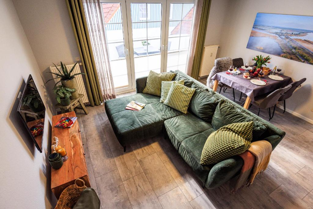 a living room with a green couch and a table at Birkenstraße 6 Haus II Whg5 in Zingst