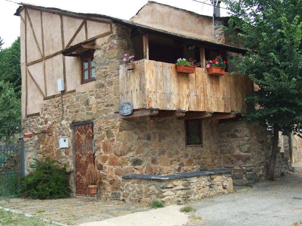 um edifício de pedra com uma varanda com flores em Casa Aurora em San Esteban del Toral
