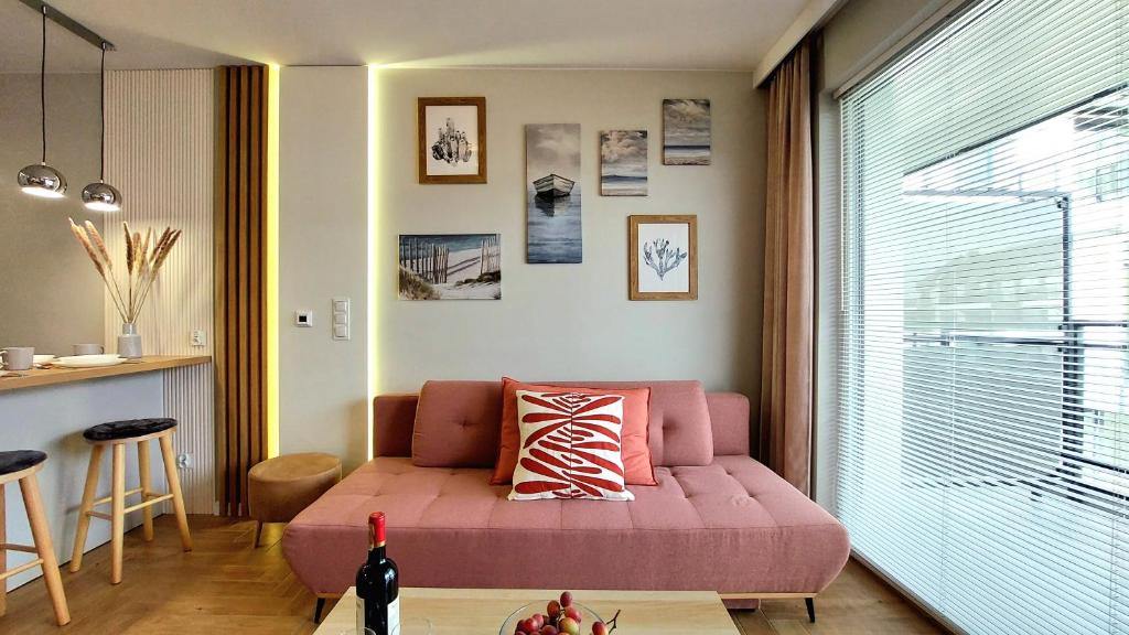 a living room with a pink couch in front of a window at Jantar Resort Złote Piaski Jantaru by TriApart in Jantar