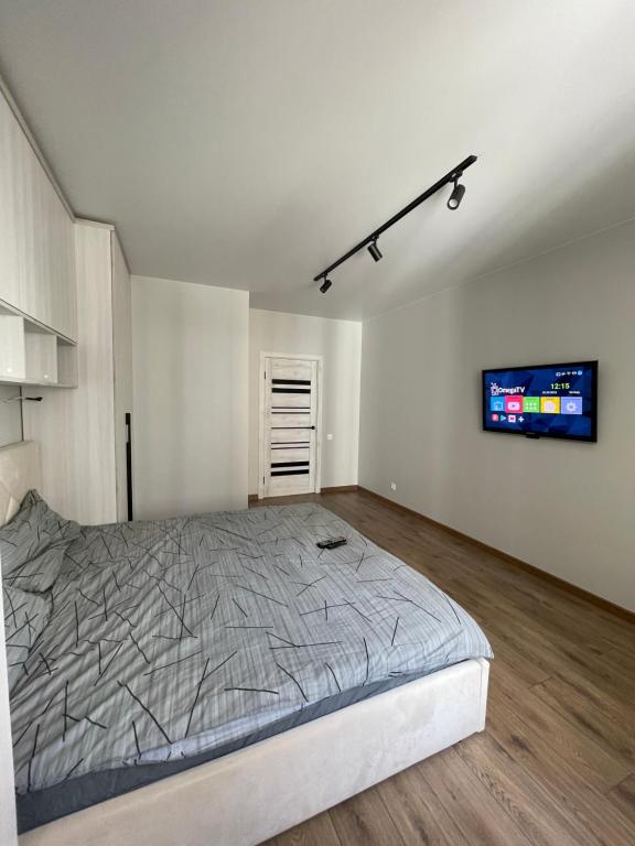 Schlafzimmer mit einem Bett und einem Flachbild-TV in der Unterkunft Квартира в парку біля озера, 10 хв до центра, 1км in Ternopil