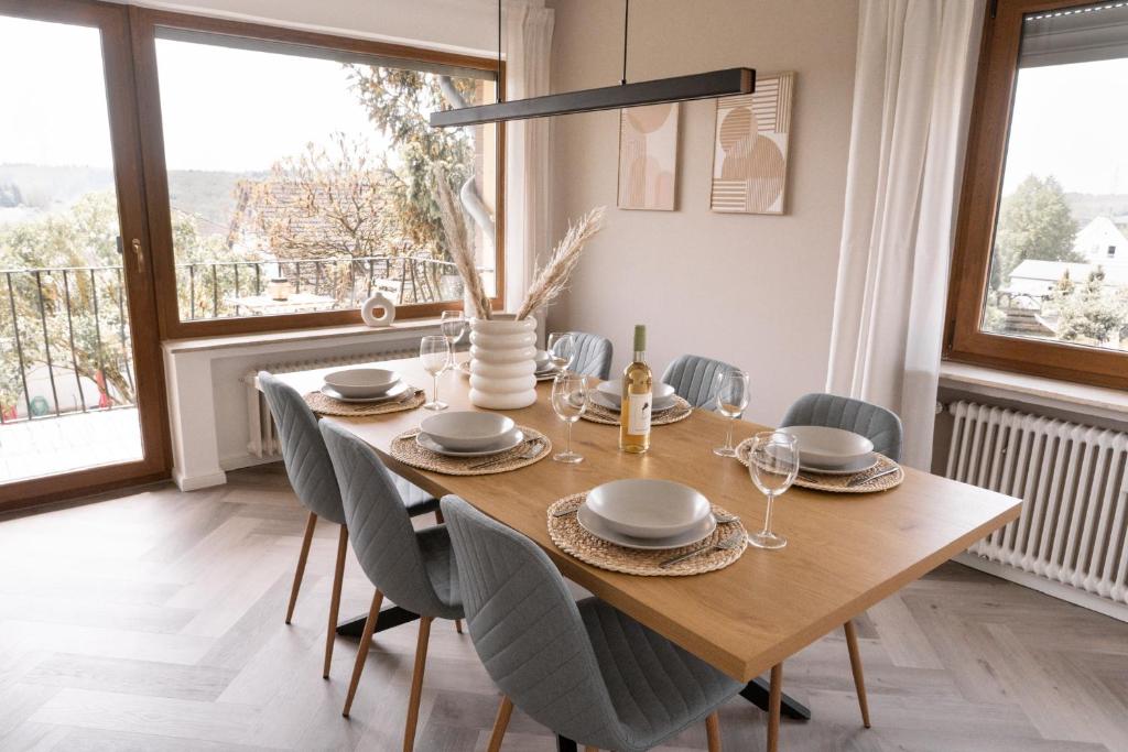 uma sala de jantar com uma mesa de madeira e cadeiras em TRIMOSA Apartments - cozy, modern und citynah em Trierweiler