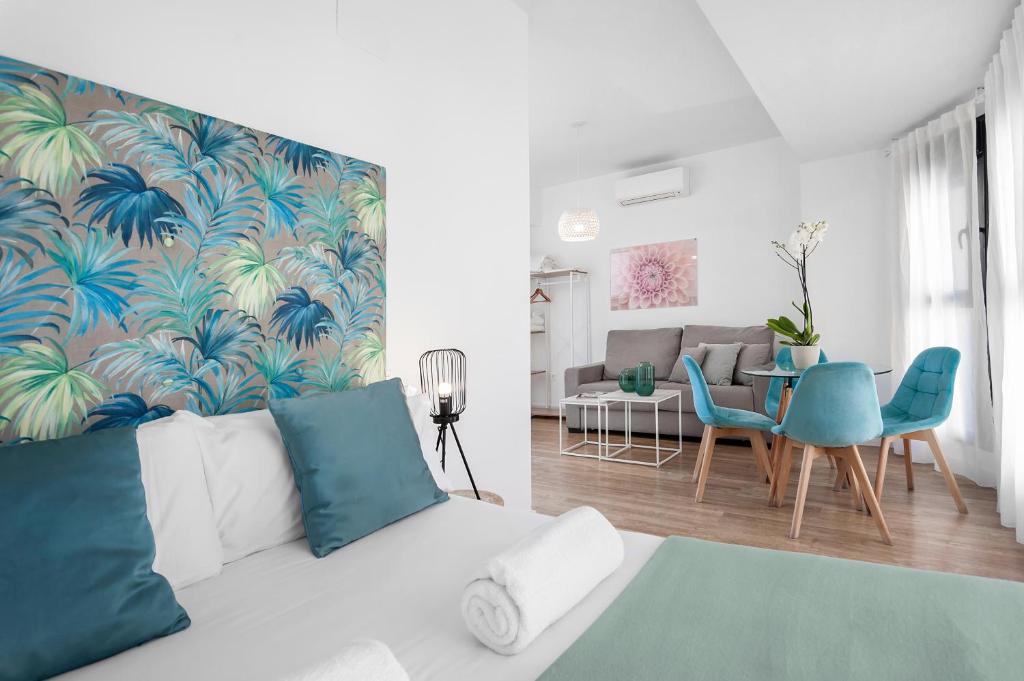 sala de estar con sofá blanco y sillas azules en Apartamentos de Isabella, en Granada