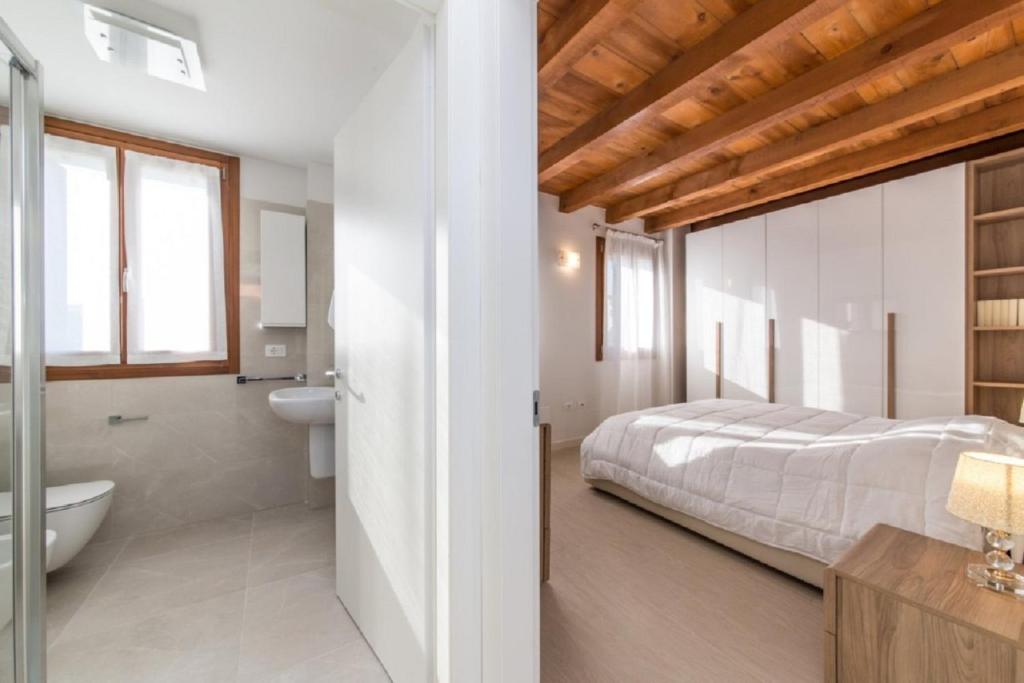 a bedroom with a bed and a bathroom with a tub at Pellestrina Domus - Italianflat in Venice