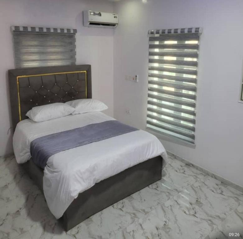 a bedroom with a large bed and two windows at PLOT 36 APARTMENT in Lekki