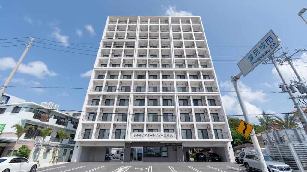 um edifício branco alto com um cartaz em ホテルエアポートビューNAHA em Gushi