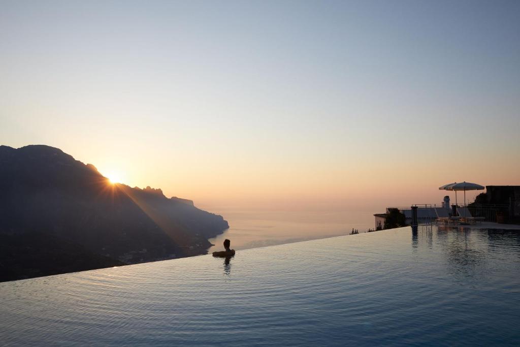 een persoon zit in het water bij een overloopzwembad bij Caruso, A Belmond Hotel, Amalfi Coast in Ravello