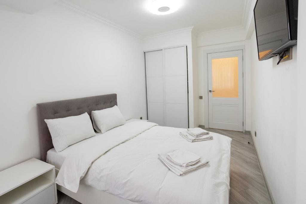 biała sypialnia z białym łóżkiem i telewizorem w obiekcie Apartament in the Center Area w mieście Sectorul Botanica