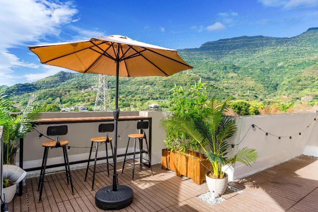 a patio with an umbrella and some plants and mountains at H& Kuma B&B in Jian