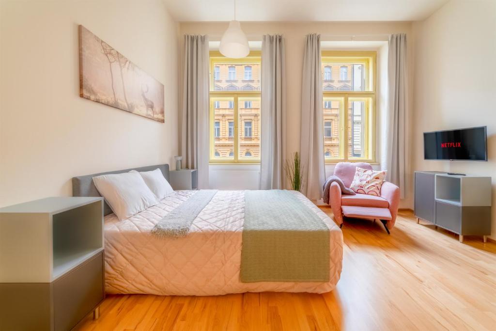 een slaapkamer met een bed, een stoel en een raam bij Historic City Center Deer Suite by Rentez in Praag