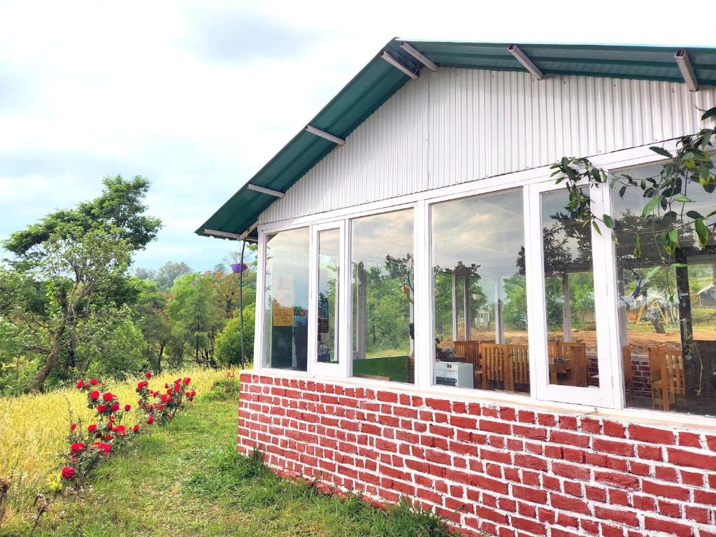 比爾的住宿－Hipostel Bir - Stay and Cafe，草上带窗户和鲜花的砖砌建筑