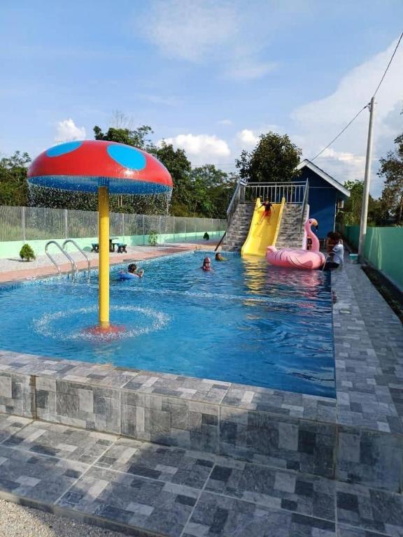 - une piscine avec toboggan et parasol dans l'établissement D cateleya homestay, à Beranang