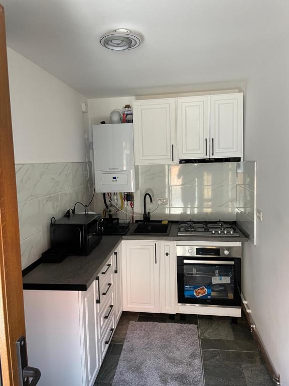 a small kitchen with white cabinets and a stove at White River 60 in Câmpulung Moldovenesc