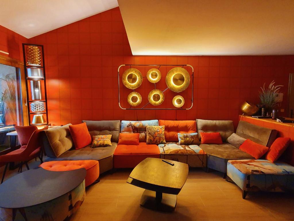 un salon avec un canapé sectionnel et des murs orange dans l'établissement Val de Pôme 6pers piscine parking 25min pied plage, à Biot