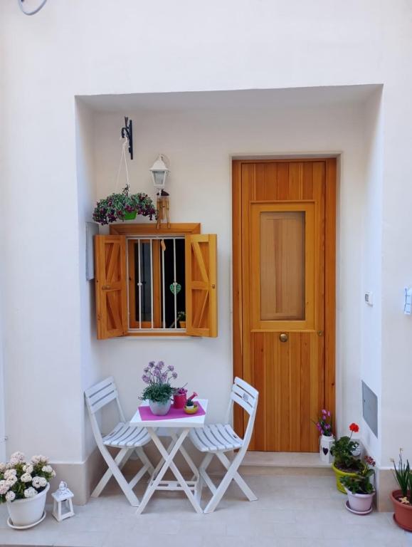 a patio with a table and chairs and a wooden door at Residenza Ronna Razia in Avola