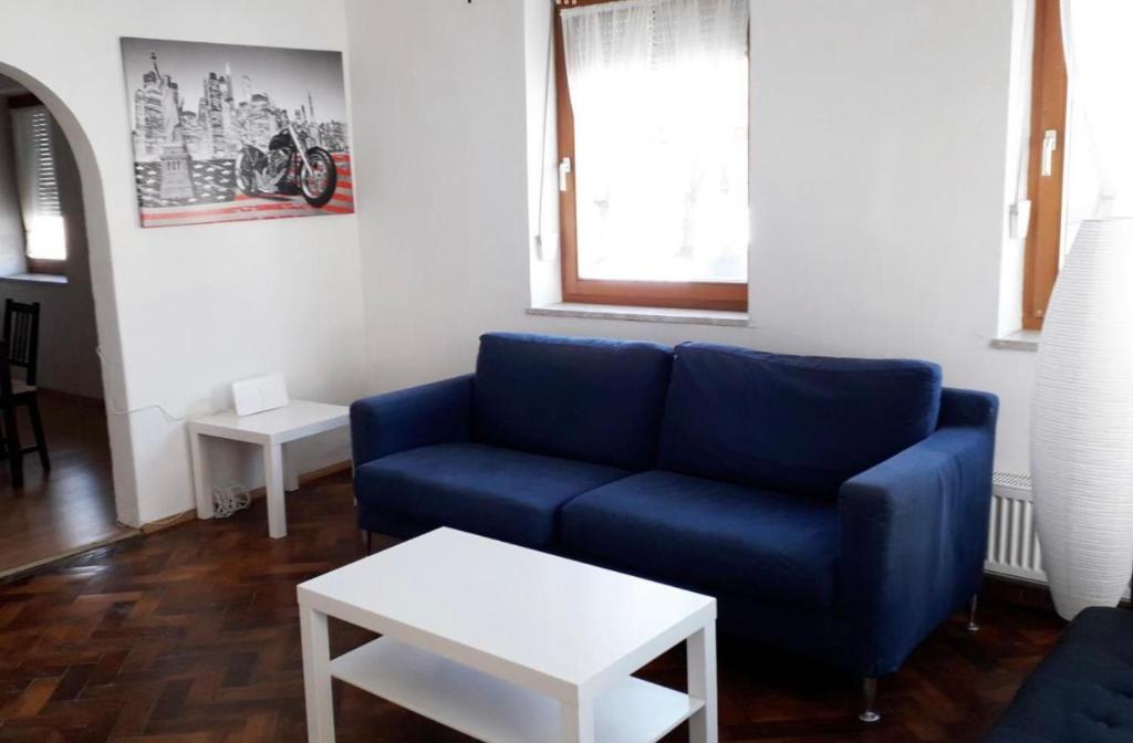 a living room with a blue couch and a table at home2stay Worker House Feldstetten Kitchen,Wifi,Smart TV Parking *** in Laichingen