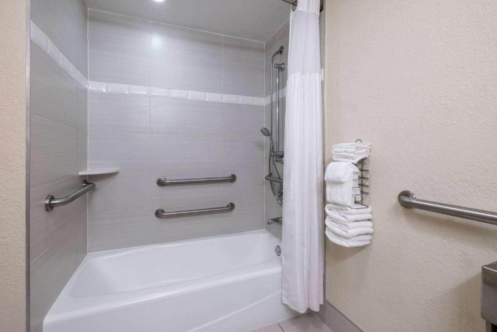 a bathroom with a tub and a shower with towels at Wyndham Boca Raton Hotel in Boca Raton
