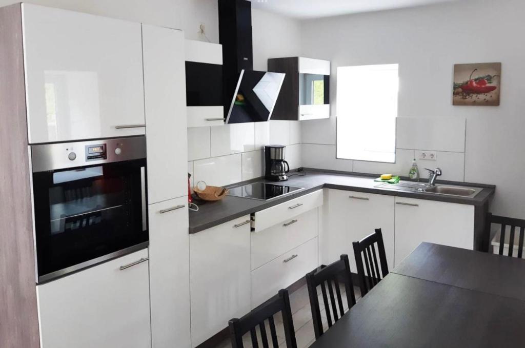 a kitchen with white cabinets and a table with chairs at home2stay Worker Houses Wernau Kitchen,Wifi,Smart TV,Parking *** in Wernau