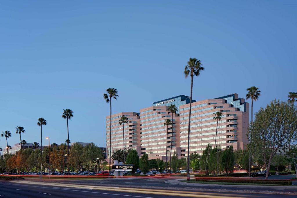 a large building with palm trees in front of a street at Hyatt Regency Santa Clara in Santa Clara