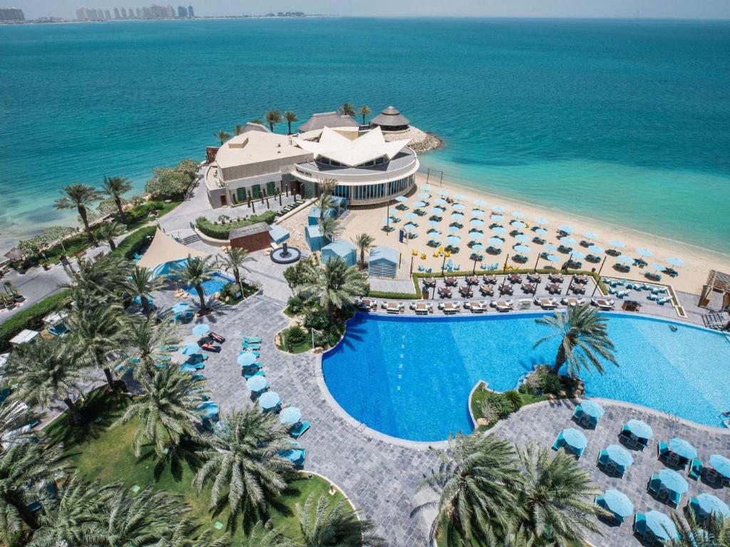 an aerial view of a resort with a pool and the ocean at Hilton Doha in Doha