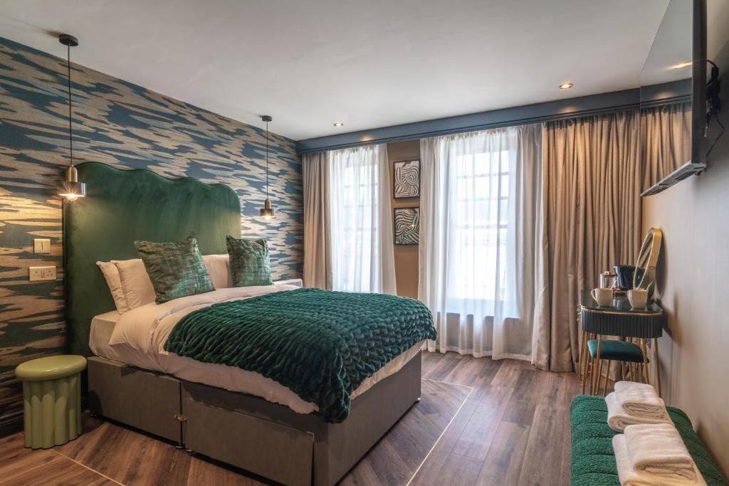 ein Schlafzimmer mit einem großen Bett und einer grünen Decke in der Unterkunft Howfield Hotel in Merthyr Tydfil