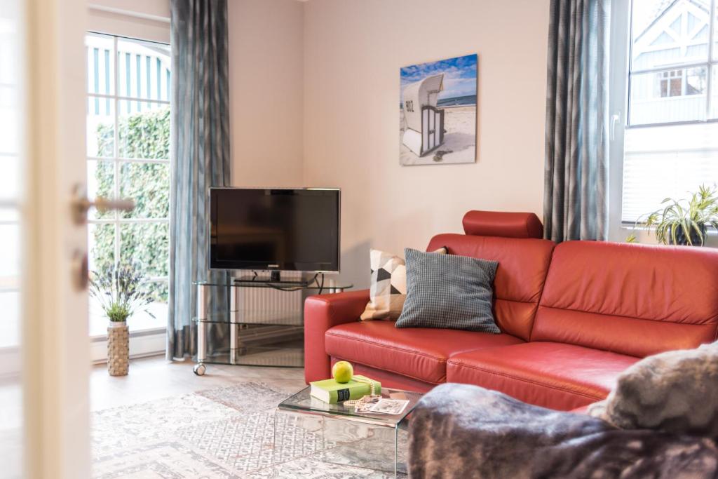 a living room with a red couch and a flat screen tv at Birkenstraße 6 Haus II Whg1 in Zingst