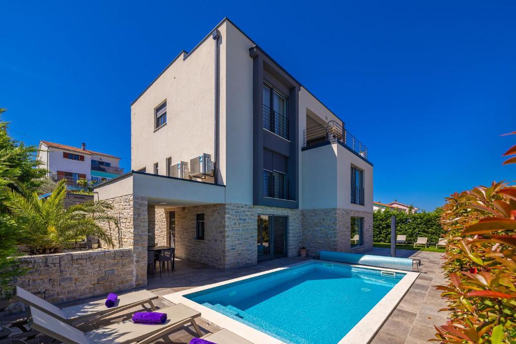 een huis met een zwembad ervoor bij Apartman SIORA in Njivice