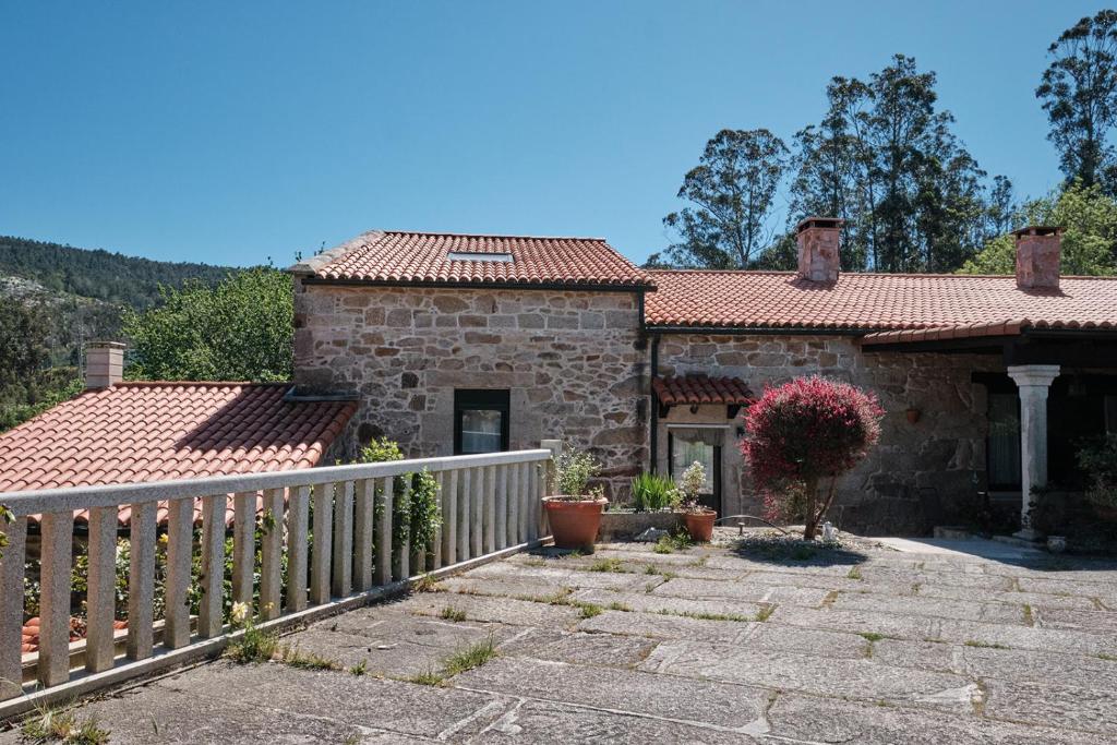 a stone house with a fence in front of it at Entre Pedra e Mar by Serendipia Turismo in Goyanes