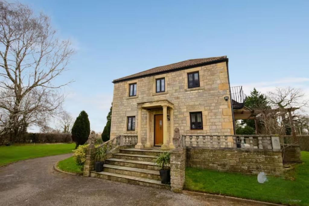 a stone house with a yellow door at Guest Homes - Longscroft Manor in Bradford on Avon