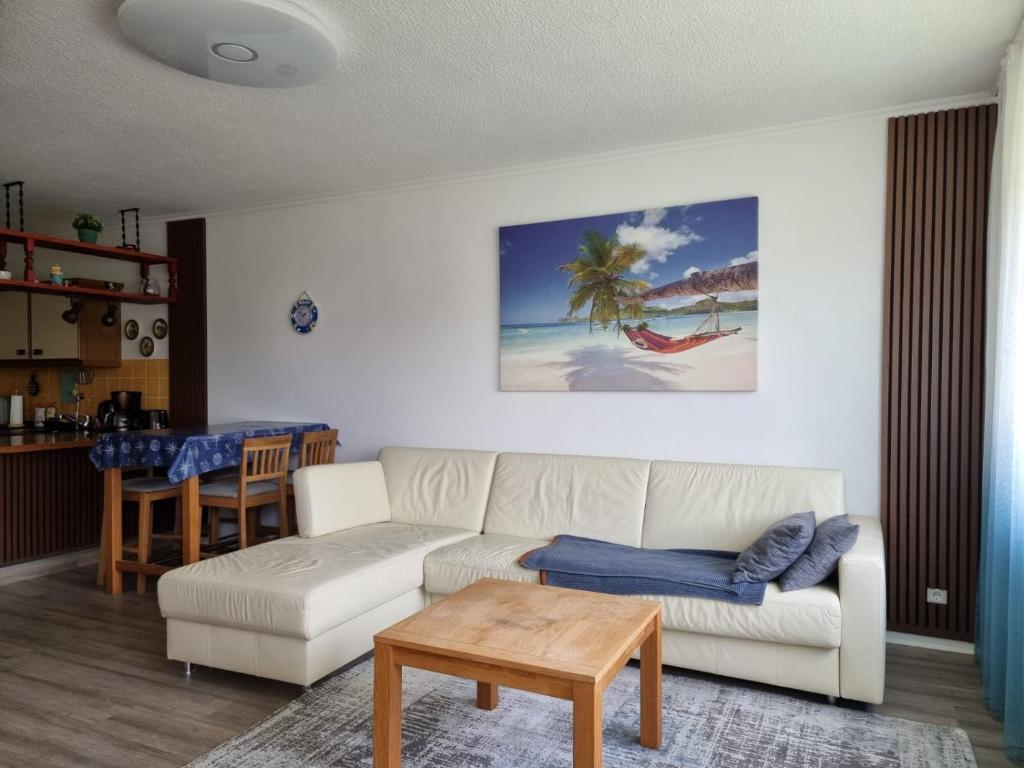 ein Wohnzimmer mit einem weißen Sofa und einem Tisch in der Unterkunft Kajüte in Timmendorfer Strand