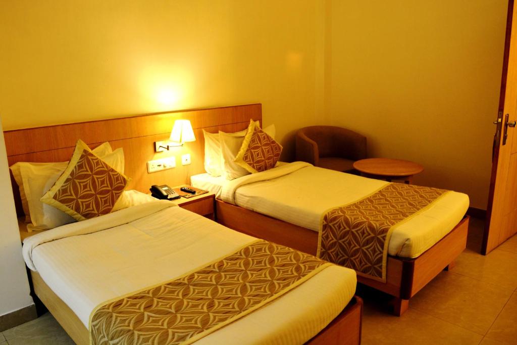 a hotel room with two beds and a chair at HOTEL KRRISH in Patna