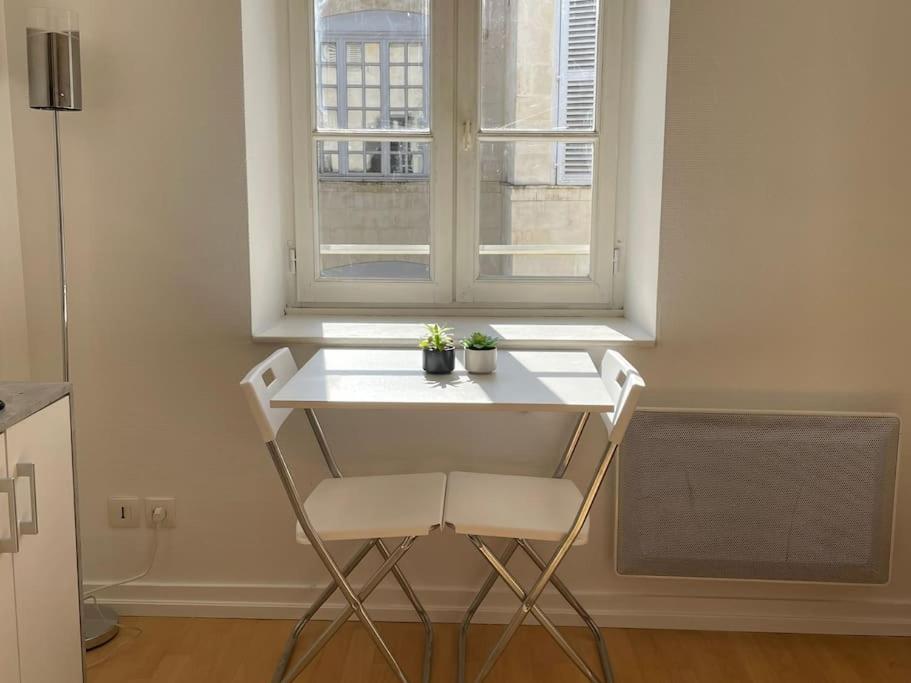 une table et des chaises blanches devant une fenêtre dans l'établissement Studio, hyper centre La Rochelle, à La Rochelle