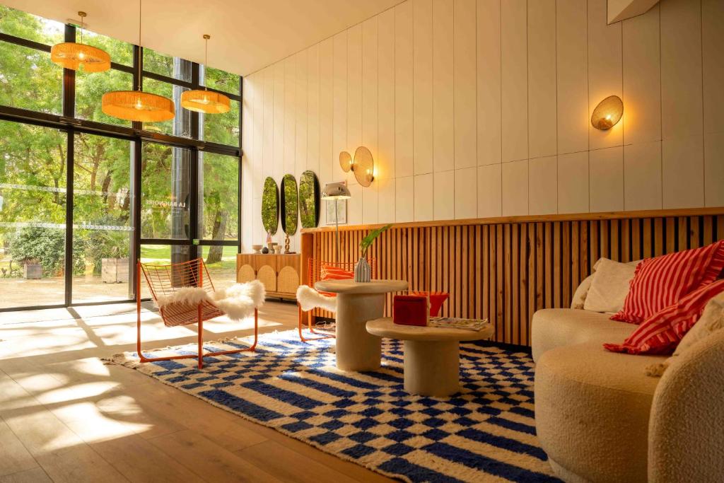 a living room with a couch and tables and windows at Boutique Hôtel La Baignoire in Lacanau-Océan