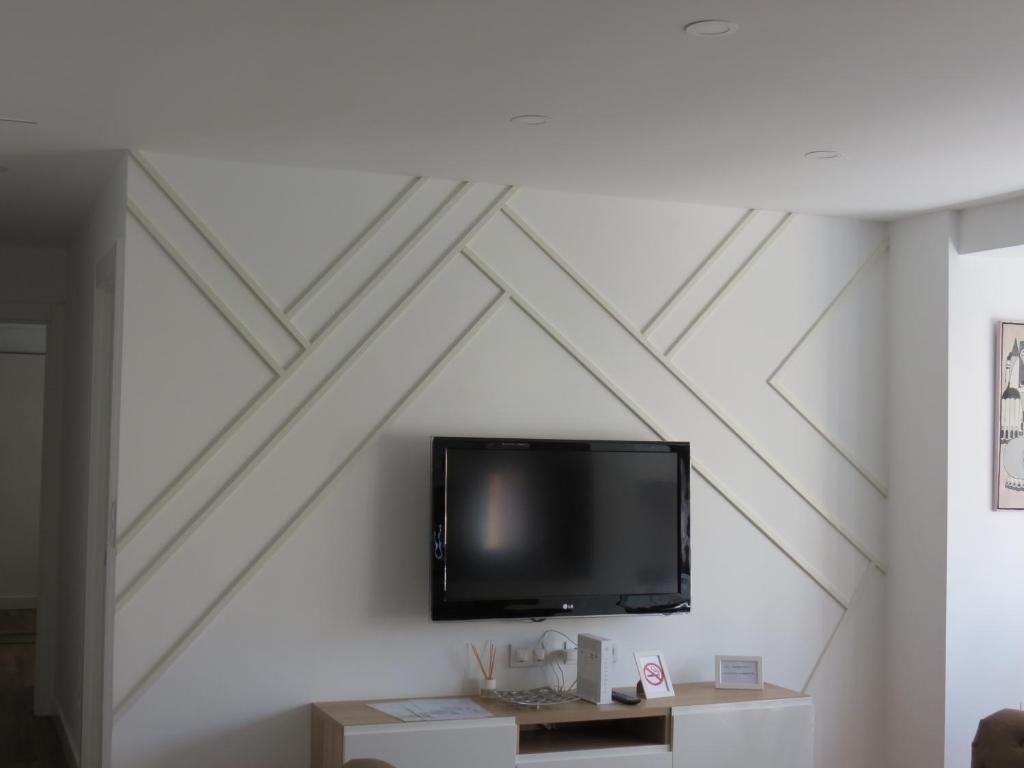 TV de pantalla plana colgada en una pared blanca en Apartamento AIRES DEL NORTE, con WiFi gratis en Santander