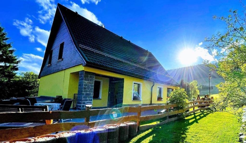 ein kleines gelbes Haus mit schwarzem Dach in der Unterkunft 3-Zimmerwohnung im Kurort Oberwiesenthal direkt an der Skipiste in Kurort Oberwiesenthal