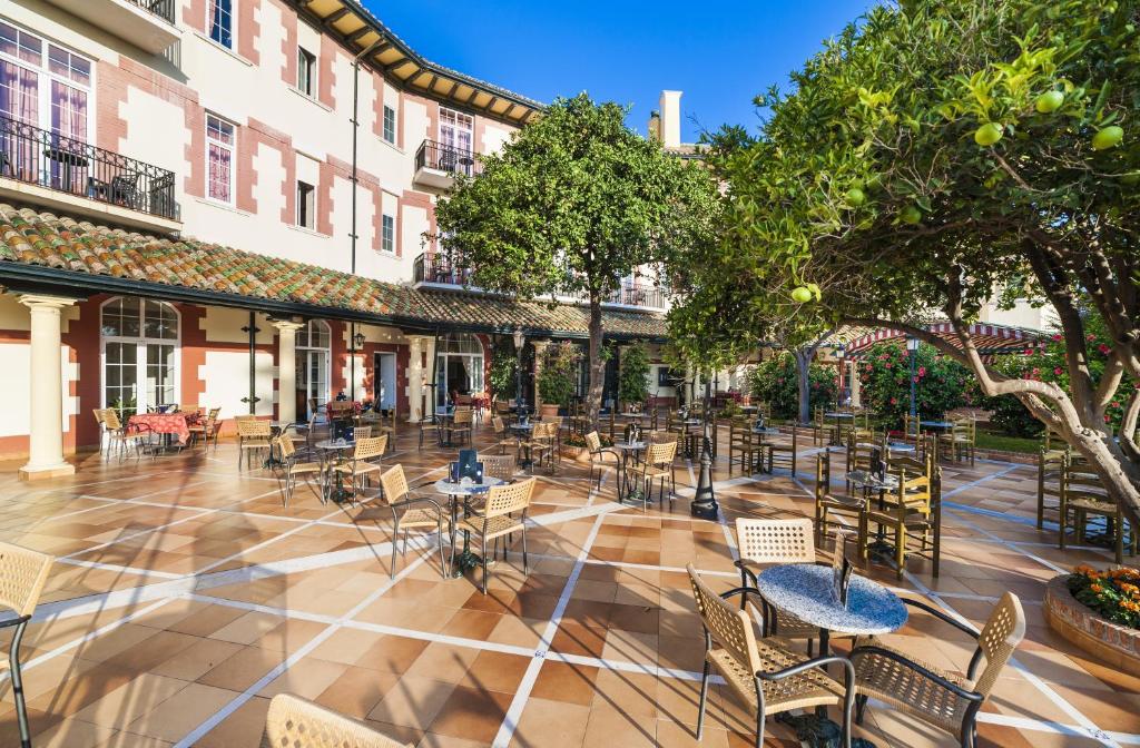 a patio area with tables, chairs and umbrellas at Globales Reina Cristina in Algeciras