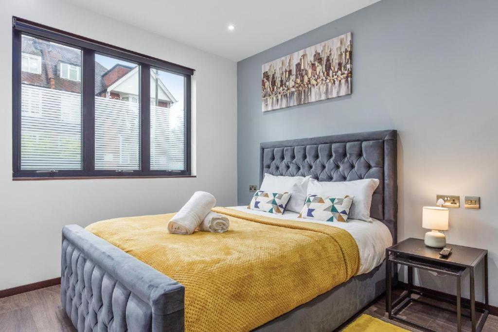 - une chambre avec un grand lit et une couverture jaune dans l'établissement Serviced Golders Green Apartment near Camden London - 2, à Londres