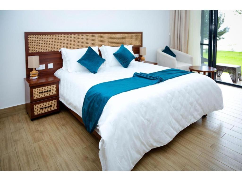 1 dormitorio con 1 cama blanca grande con sábanas azules en Eben Lake Kivu cottages and Villas 