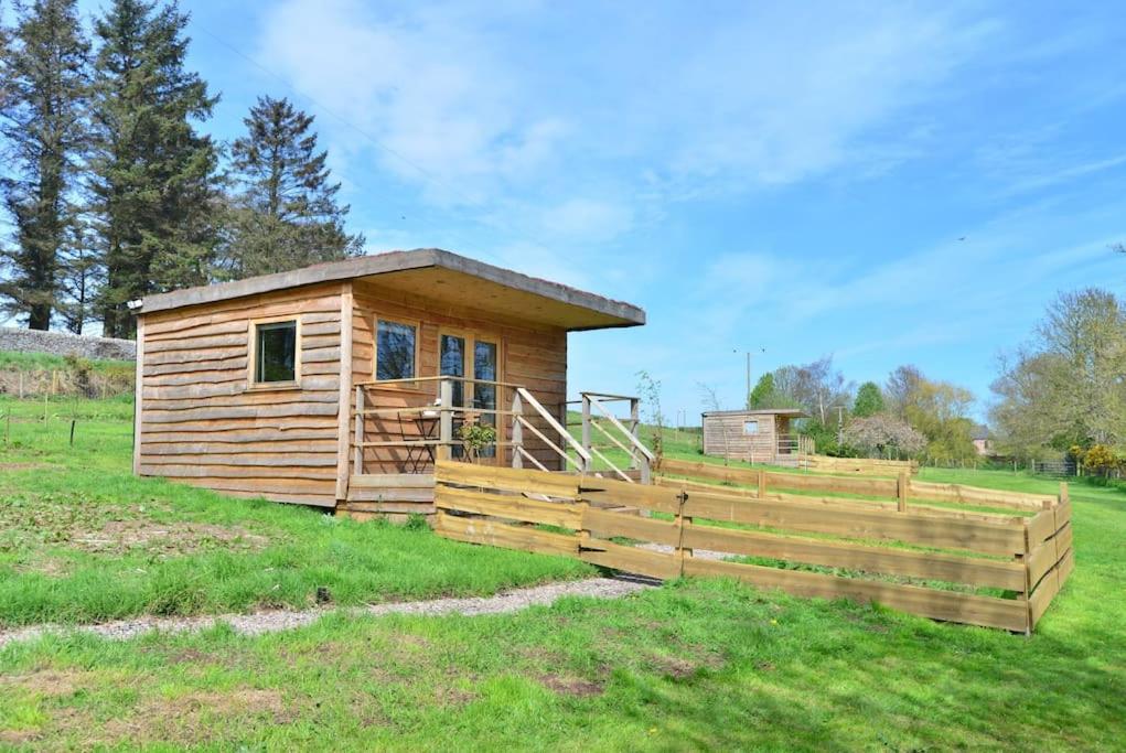 a wooden cabin in a field with a fence at Anniston Mill Cabin in Arbroath