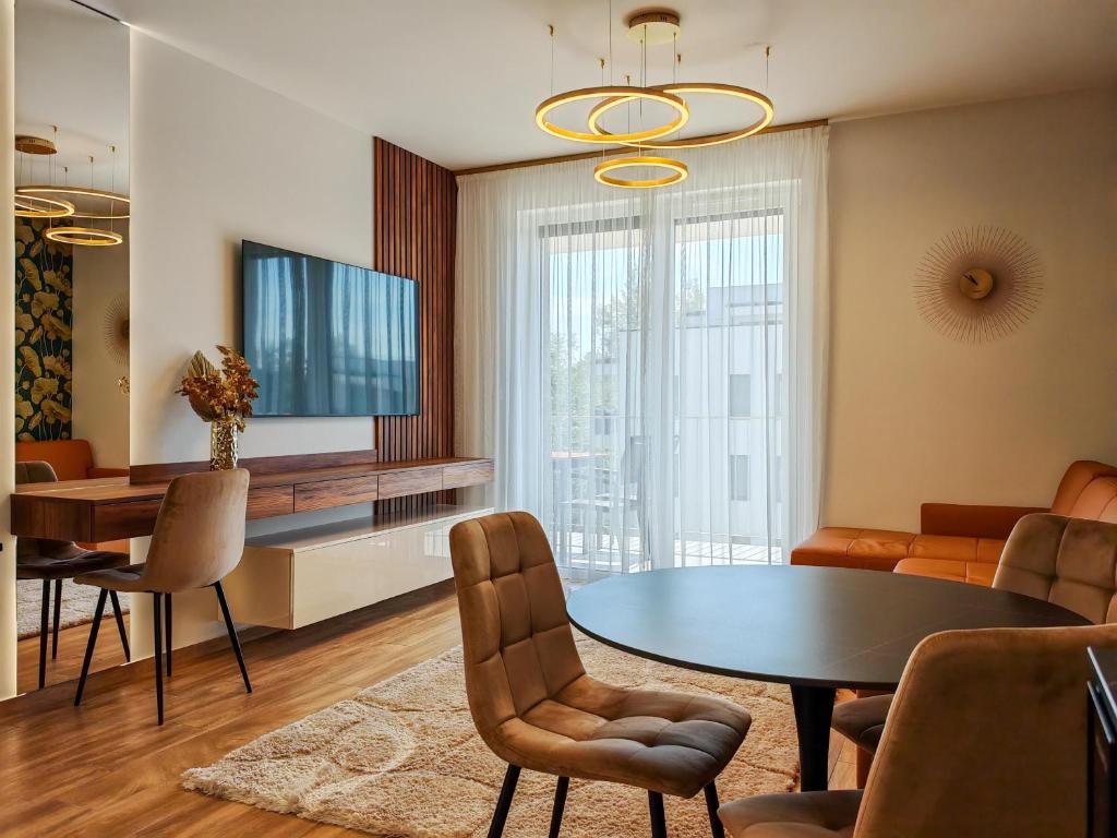 AquaSuite Budapest في بودابست: غرفة معيشة مع طاولة وكراسي وتلفزيون