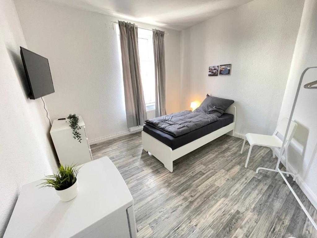 5-Zimmer Apartment in Osnabrück في أوسنابروك: غرفة نوم بسرير في غرفة بيضاء
