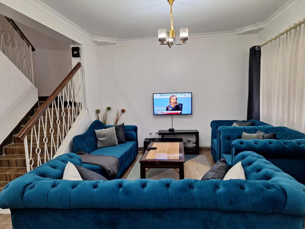 a living room with blue couches and a tv at 6th Avenue Court in Nairobi