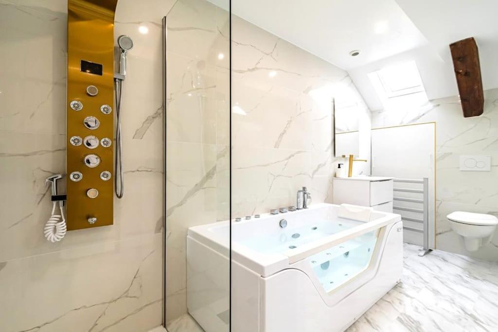 ein Badezimmer mit einer weißen Badewanne und einer Dusche in der Unterkunft Oasis Chic - Spa privé & Cinéma in Reims