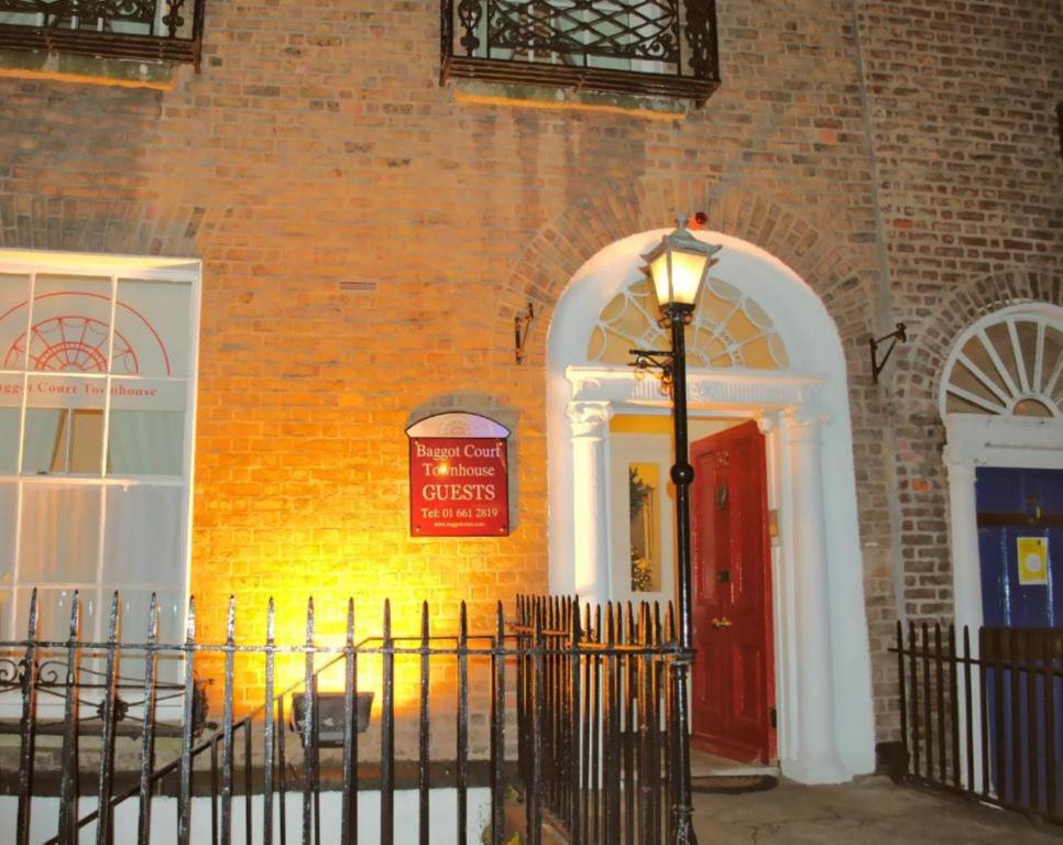 ceglany budynek z czerwonymi drzwiami i światłem ulicznym w obiekcie Baggot Court Townhouse w Dublinie