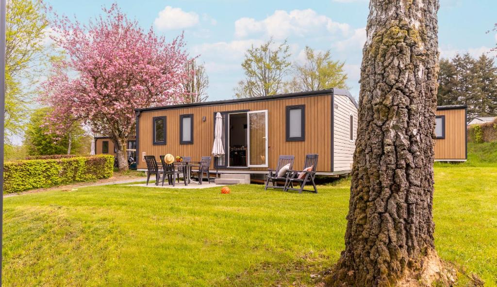 una casita en un patio con un árbol en Ardennen Camping Bertrix, en Bertrix