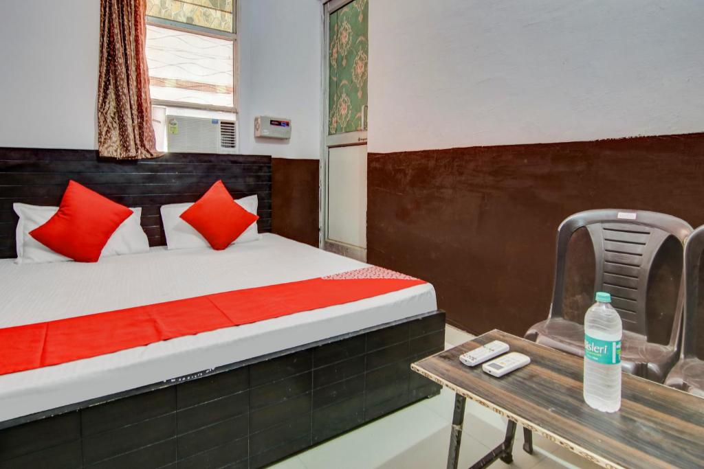 a bedroom with a bed with red pillows and a table at OYO Flagship Hotel Golden Inn in Bhiwadi
